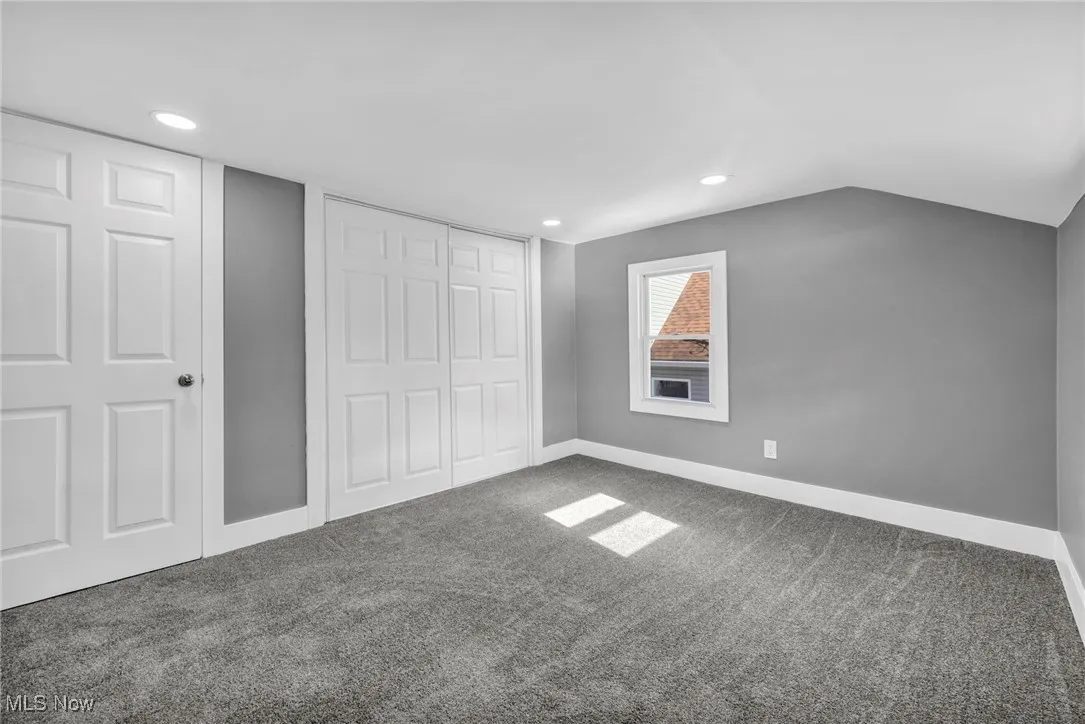 Unfurnished bedroom with carpet flooring, vaulted ceiling, a closet, and recessed lighting