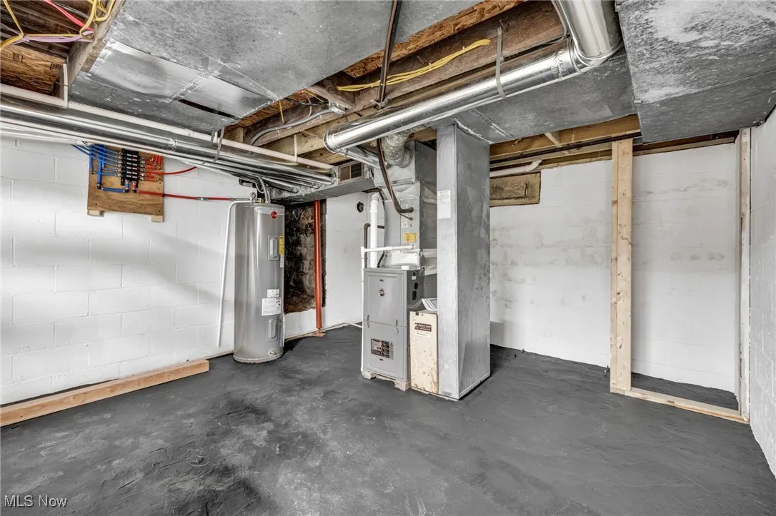 Unfinished below grade area with electric water heater and heating unit