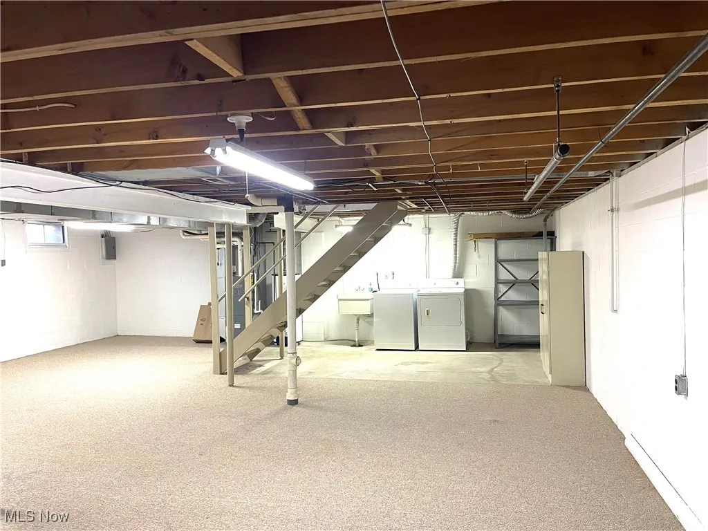 Below grade area with independent washer and dryer, stairs, and carpet flooring