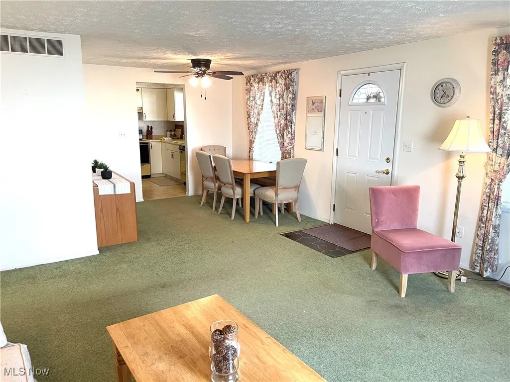 Carpeted dining space featuring a textured ceiling and a ceiling fan