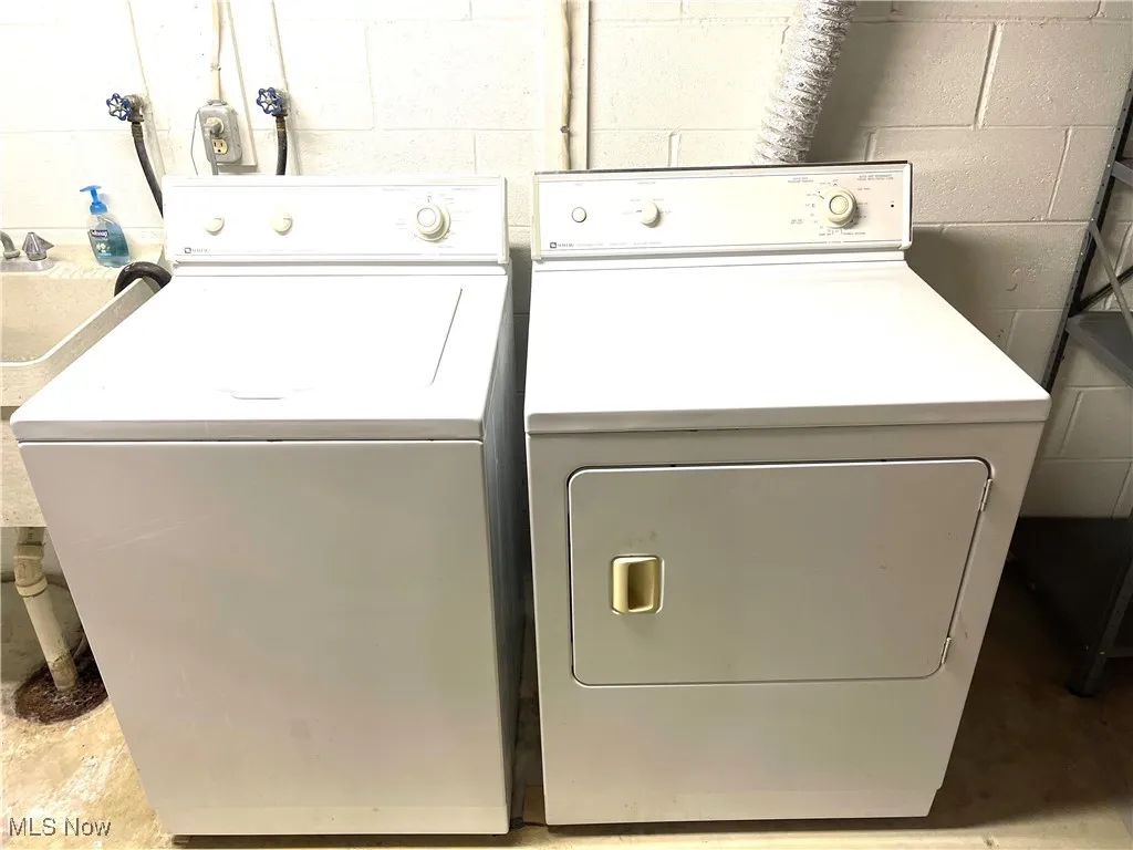 Laundry area featuring concrete block wall and washing machine and dryer