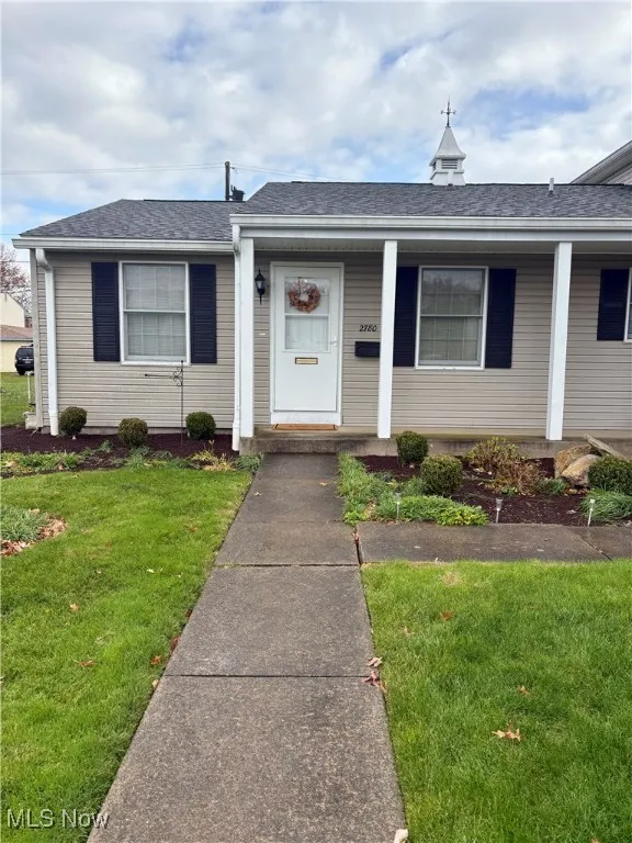 View of front of house featuring a front yard, a shingled roof, and covered porch
