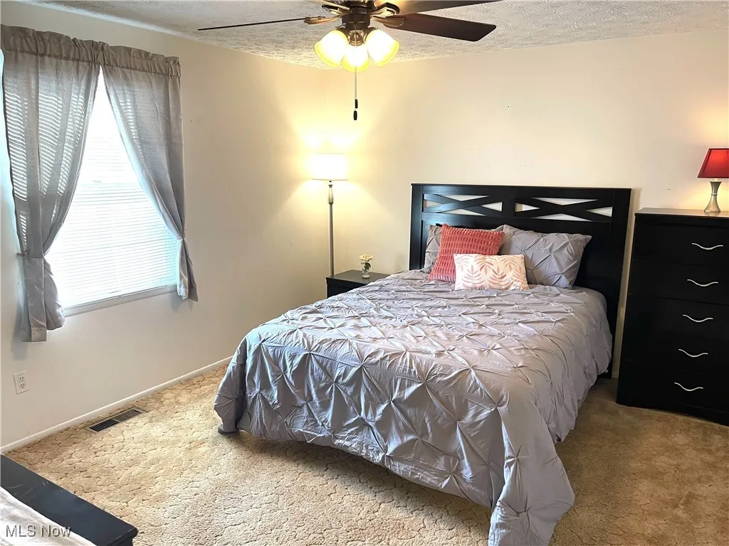 Carpeted bedroom with a textured ceiling and ceiling fan