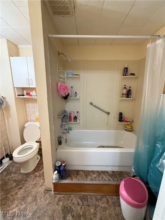 Full bathroom featuring shower / tub combo with curtain and toilet