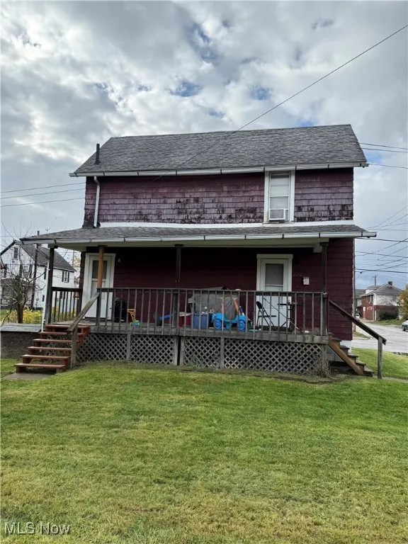 Back of property with roof with shingles, a yard, and covered porch