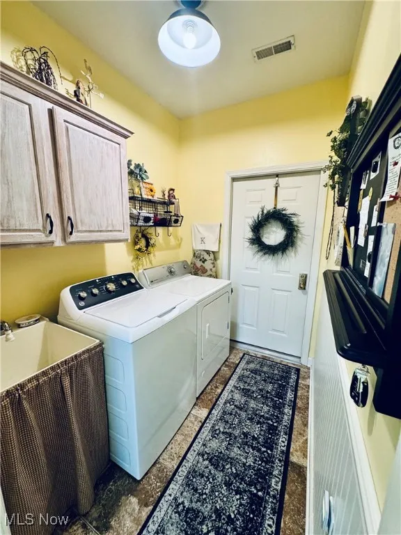 Laundry area featuring independent washer and dryer and cabinet space