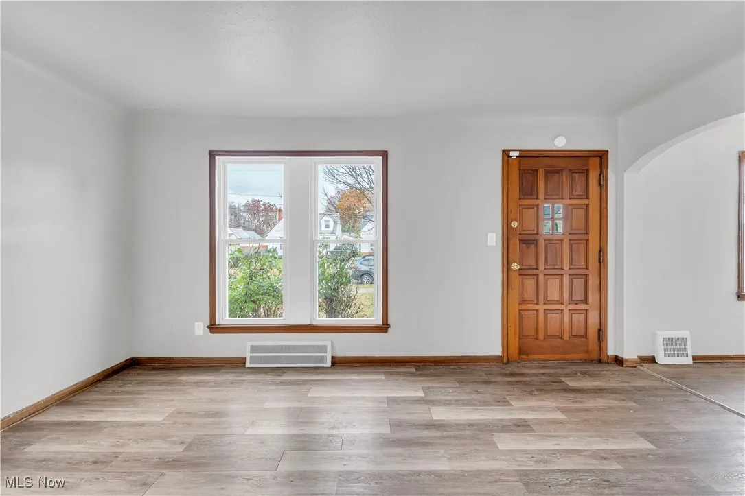 Spare room featuring arched walkways and light wood-style flooring