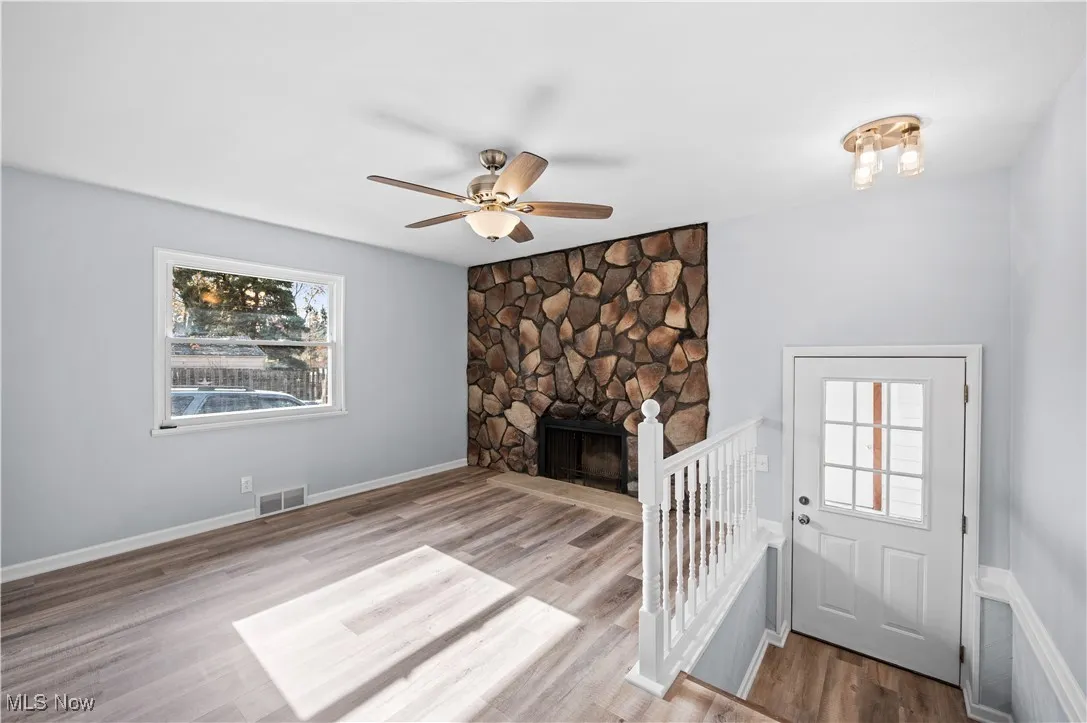Unfurnished living room with ceiling fan, light wood finished floors, and a fireplace