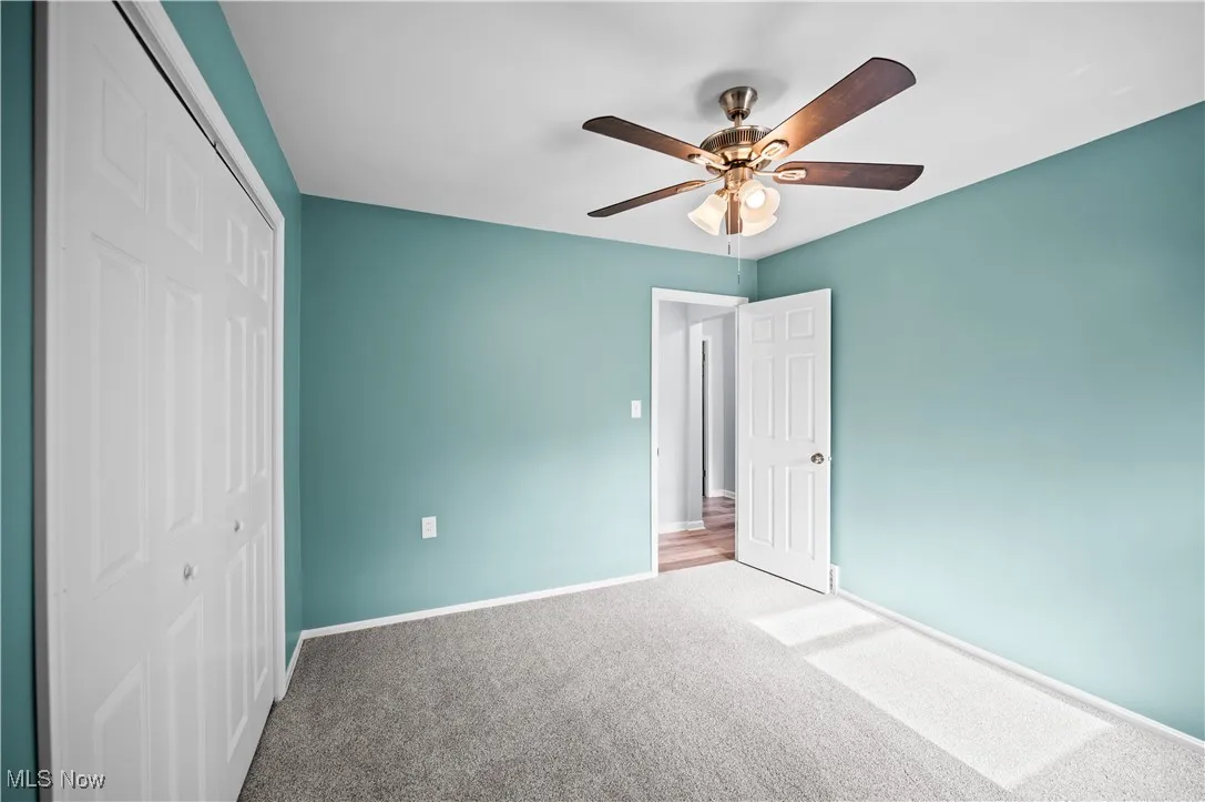 Unfurnished bedroom with carpet, a closet, and a ceiling fan