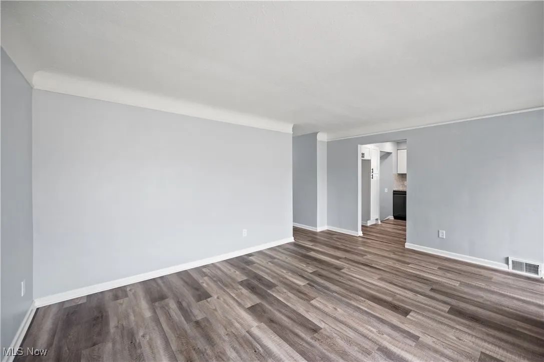 Unfurnished room with dark wood-style flooring and crown molding