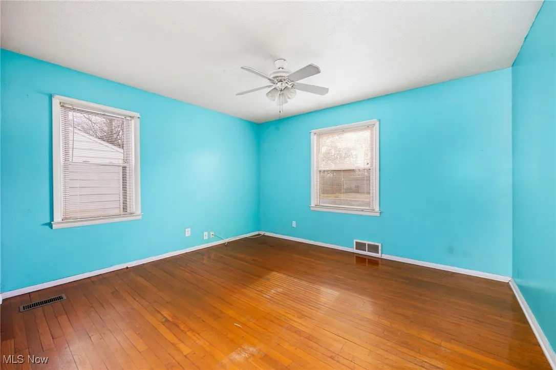 Unfurnished room with dark wood-style floors and a ceiling fan