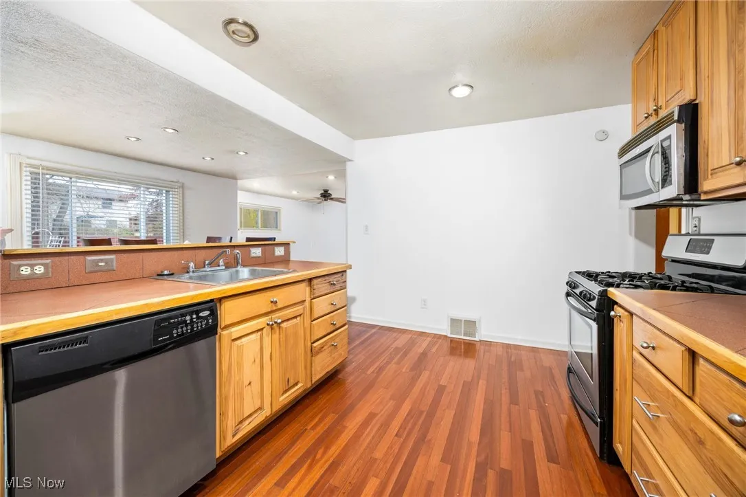 Kitchen featuring stainless steel appliances, dark wood-style floors, recessed lighting, a textured ceiling, and light countertops