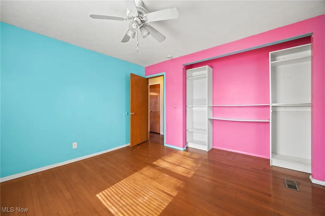 Unfurnished bedroom featuring dark wood finished floors, ceiling fan, and a closet