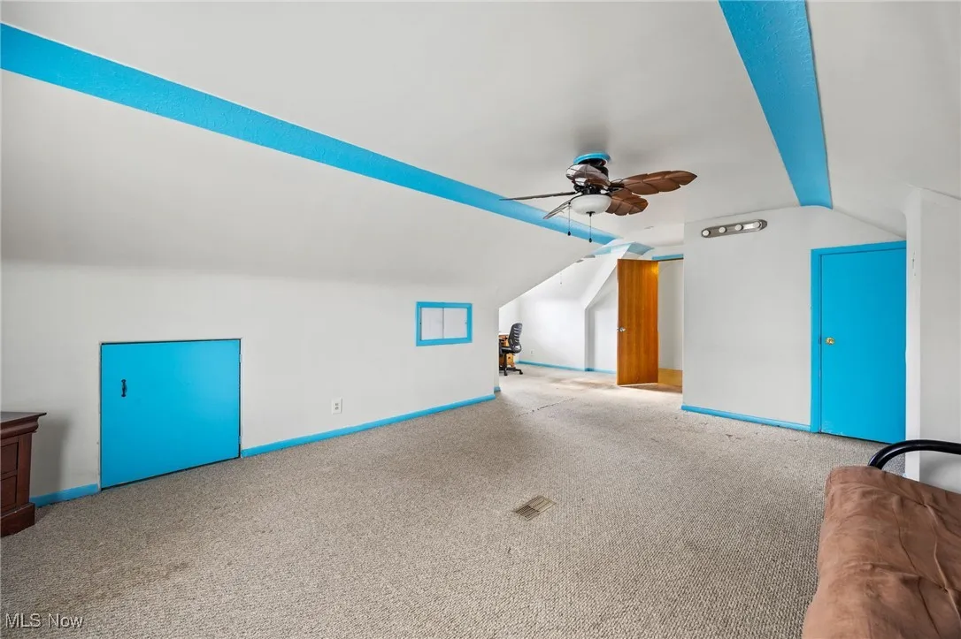 Additional living space with ceiling fan, carpet, and vaulted ceiling