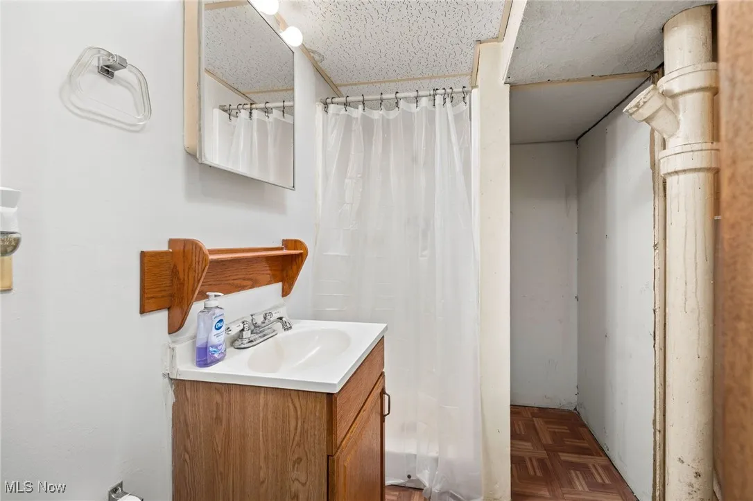 Full bathroom with vanity, a shower with shower curtain, and a textured ceiling