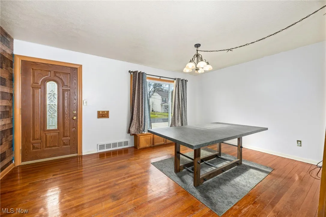 Unfurnished dining area with dark wood-type flooring and a chandelier