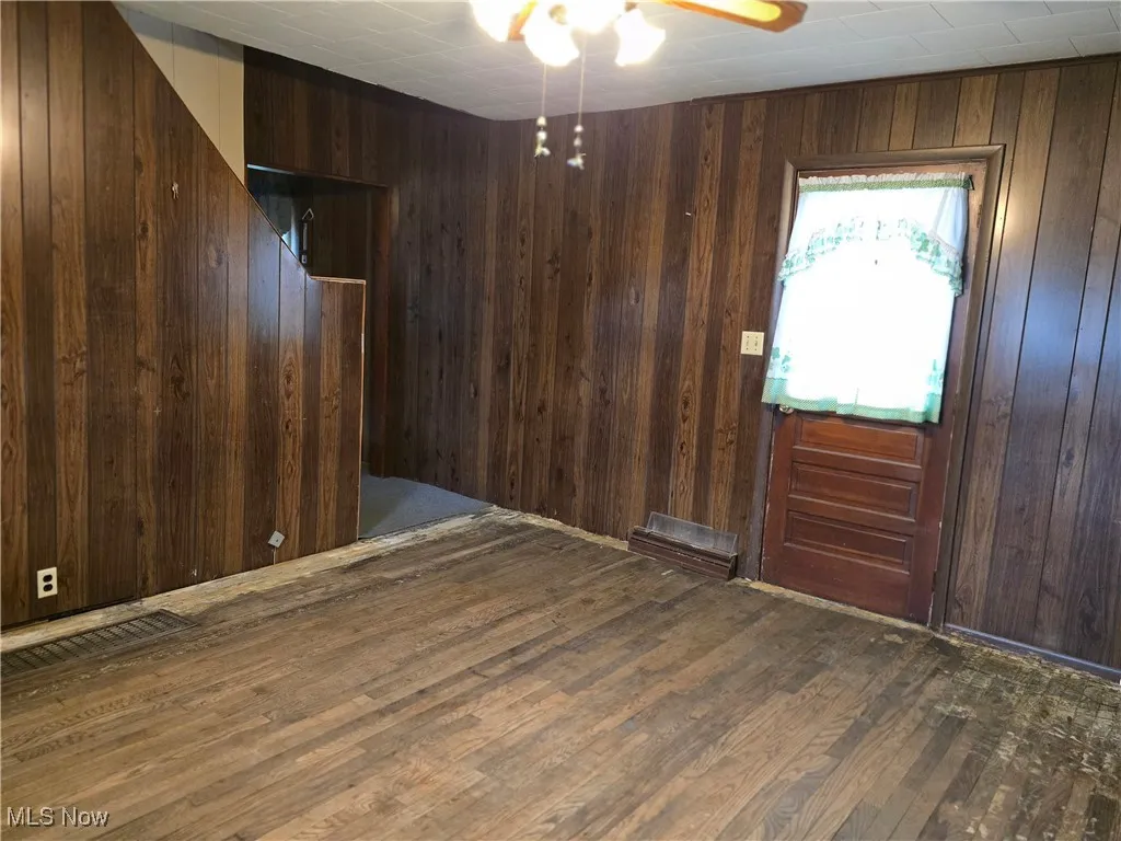 Empty room with wooden walls and dark wood-type flooring