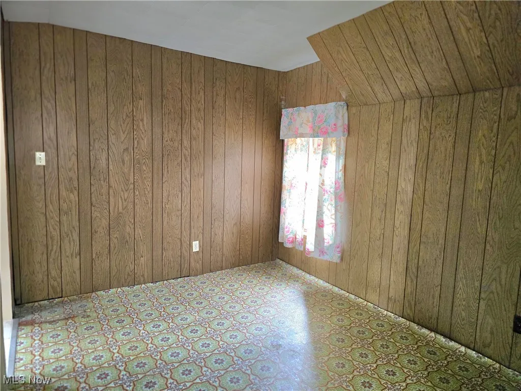 Unfurnished room featuring wood walls and tile patterned floors