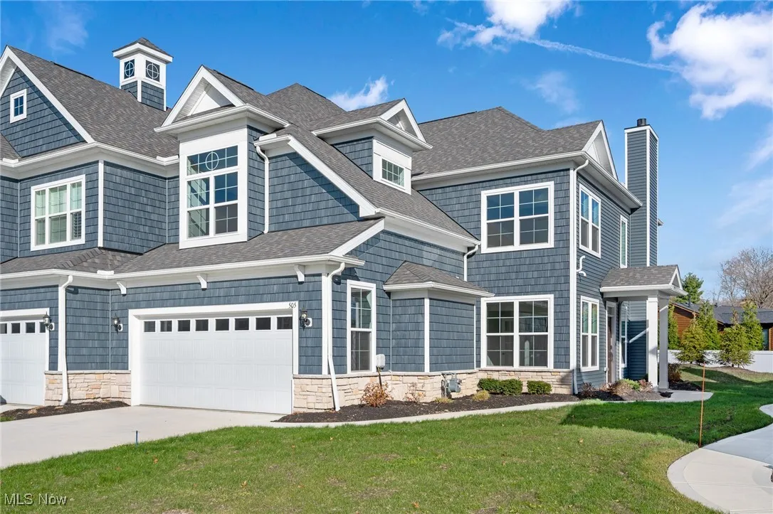 View of front of property featuring roof with shingles, a chimney, stone siding, and a front yard