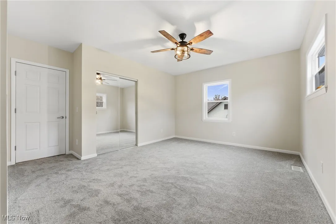 Unfurnished bedroom featuring light carpet, a closet, and a ceiling fan
