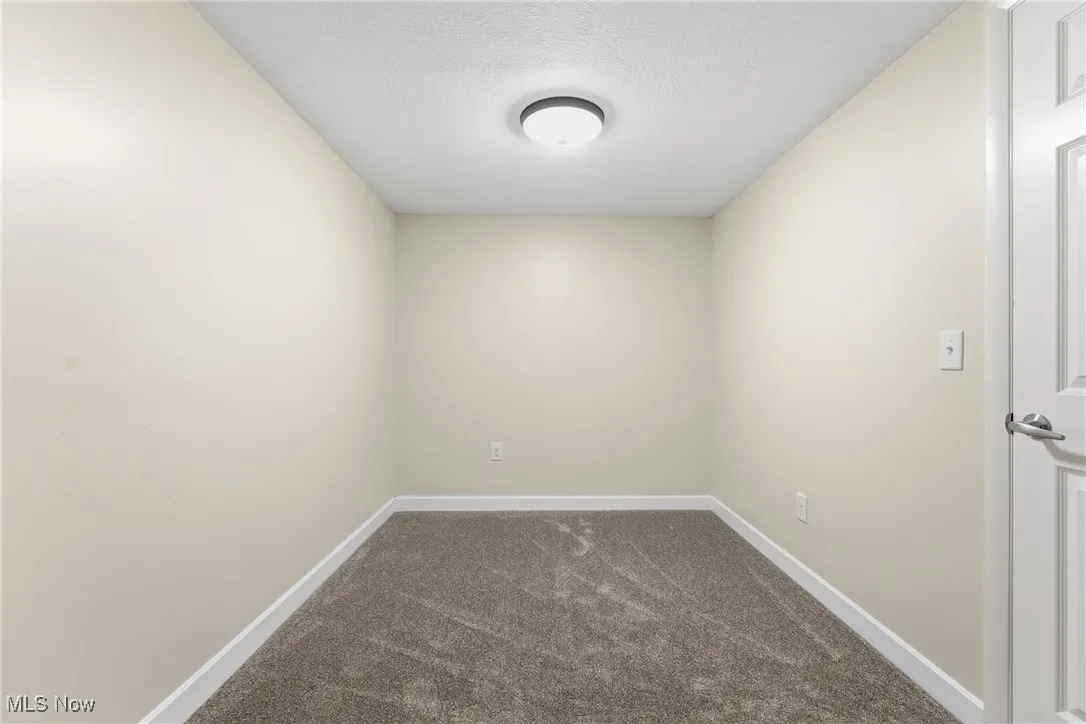 walk in closet in primary room featuring dark carpet and a textured ceiling