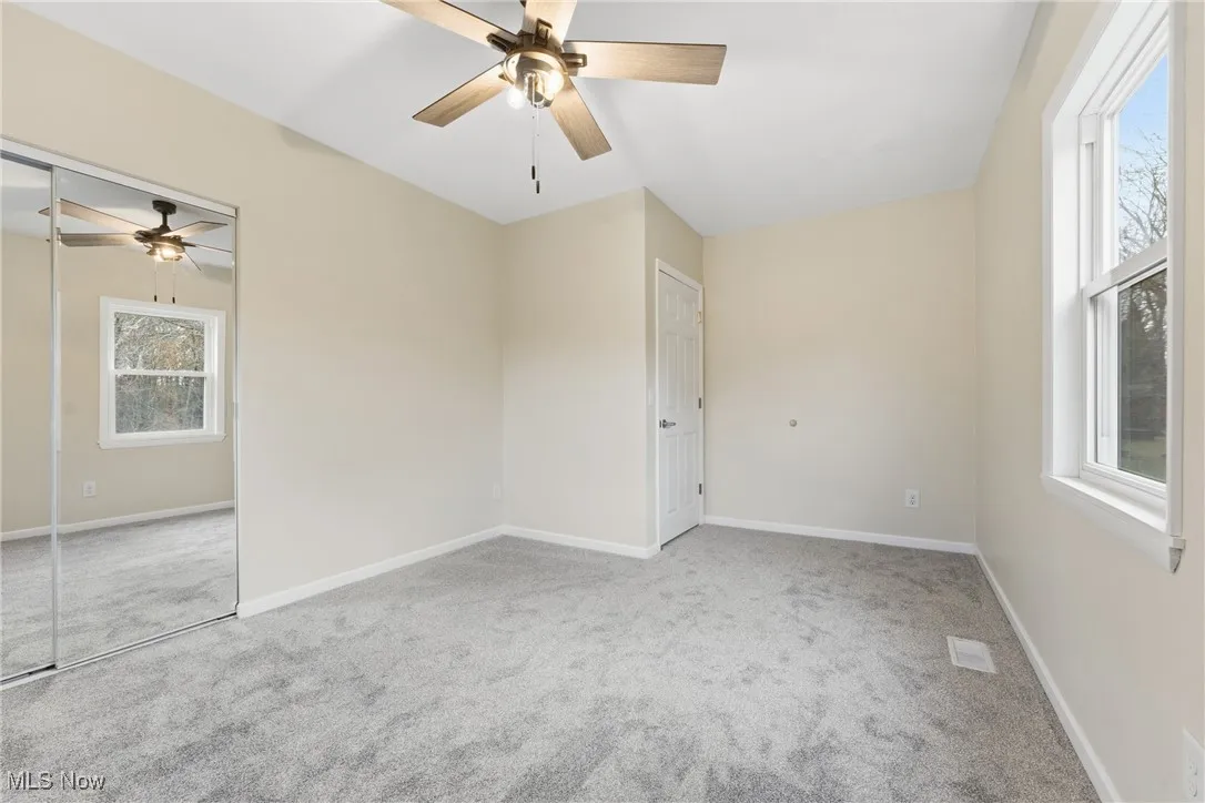 Unfurnished bedroom featuring light carpet, a closet, and a ceiling fan