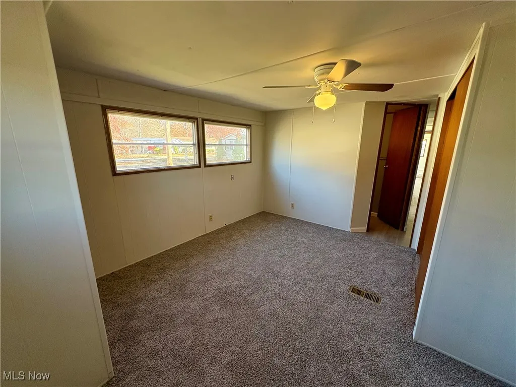Carpeted spare room with ceiling fan