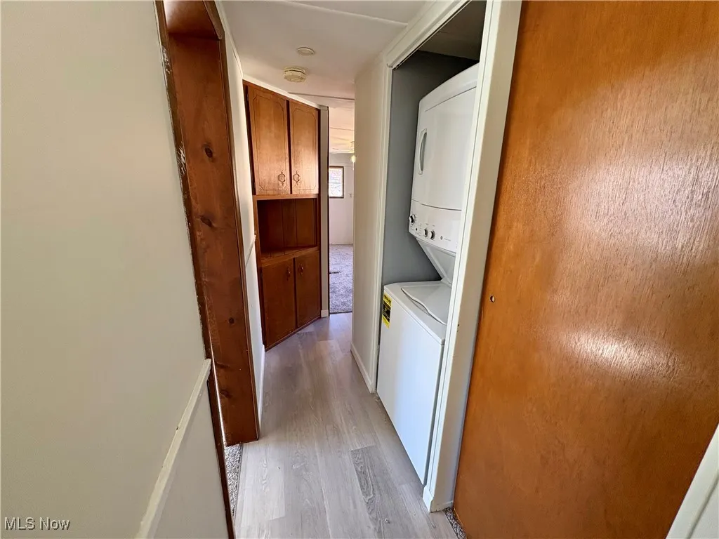 Laundry area with light wood-style flooring and estacked washer and dryer