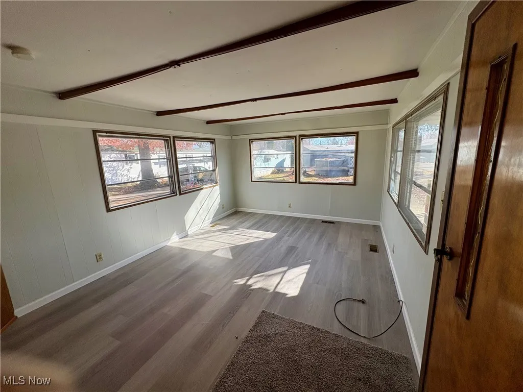 Empty room featuring beamed ceiling and wood finished floors