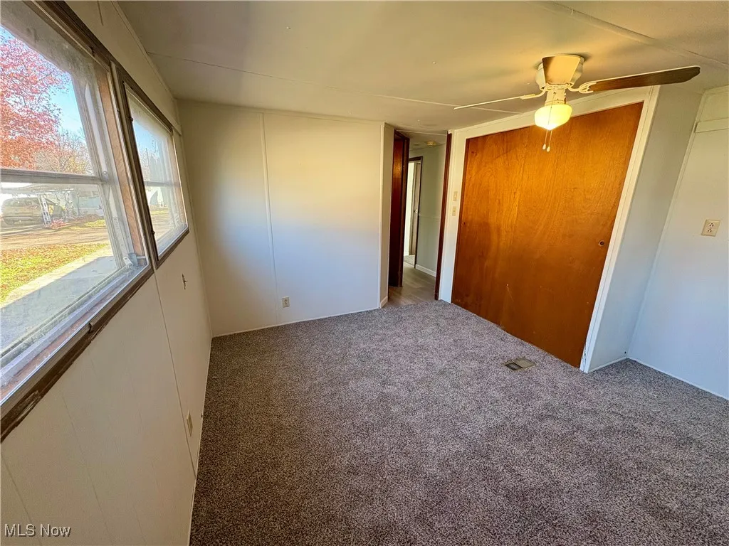 Unfurnished bedroom featuring carpet flooring, ceiling fan, and a closet