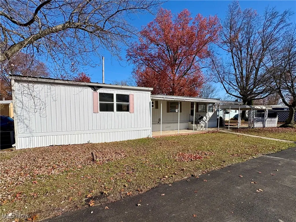 Manufactured / mobile home featuring a front yard and a carport
