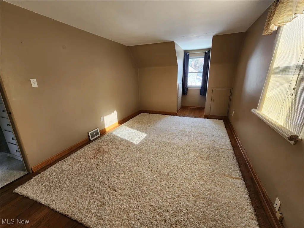Additional living space featuring dark wood-type flooring and lofted ceiling