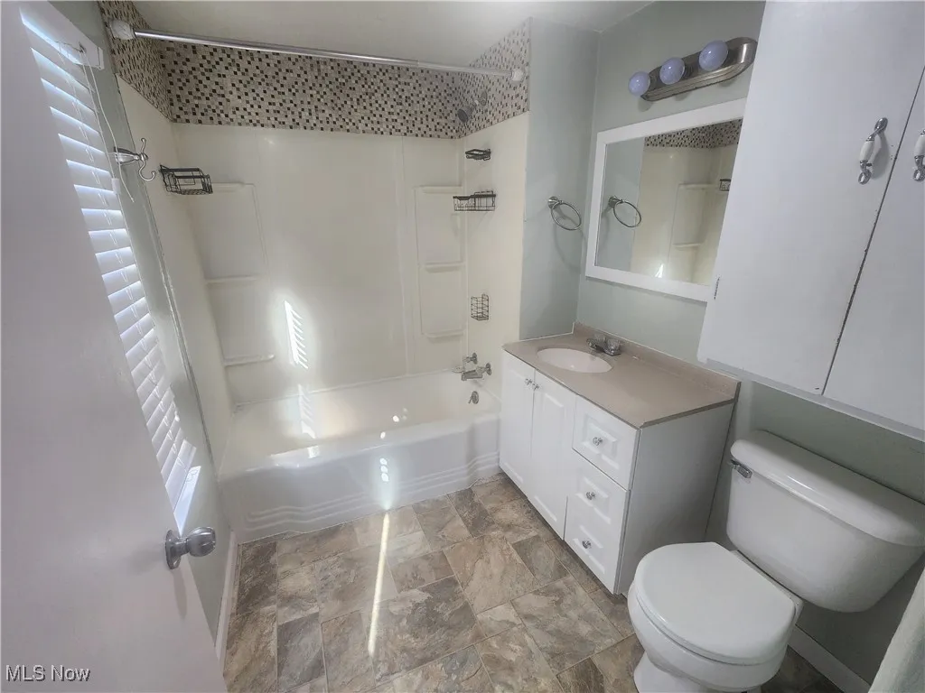 Full bath featuring shower / washtub combination, vanity, and stone finish floors