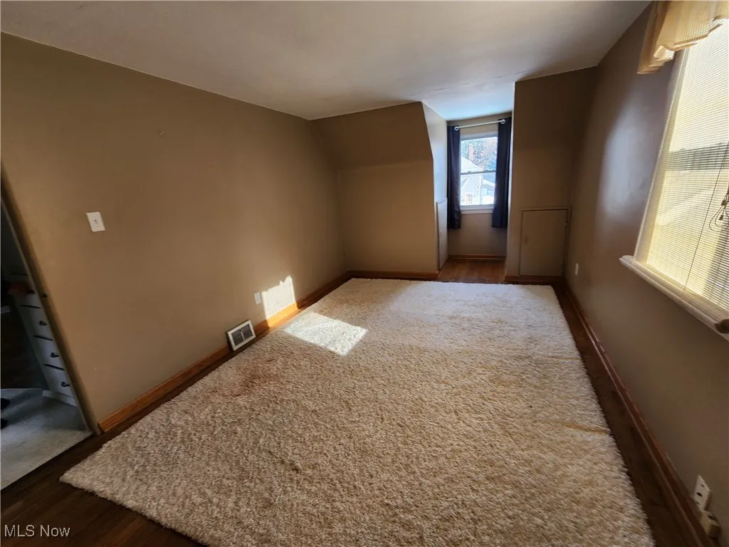 Bonus room with dark wood-style flooring and baseboards