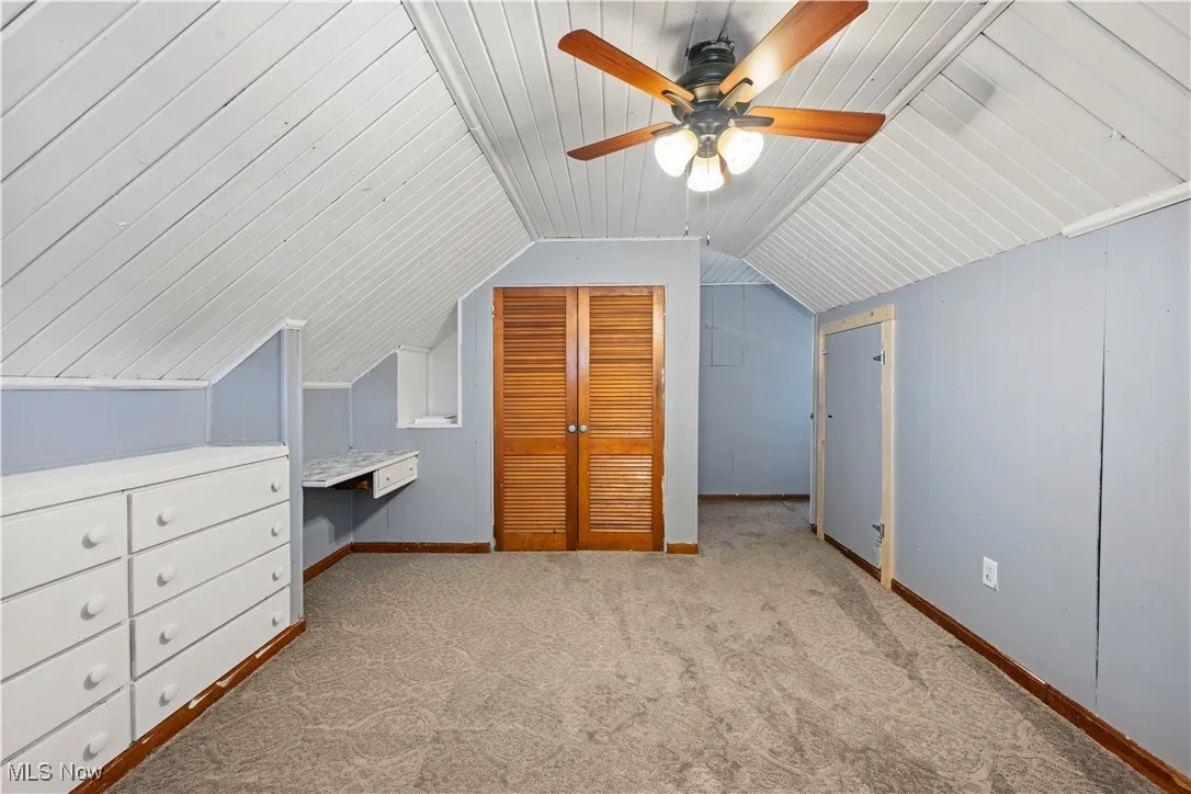 Bonus room featuring carpet floors, built in study area, vaulted ceiling, and a ceiling fan