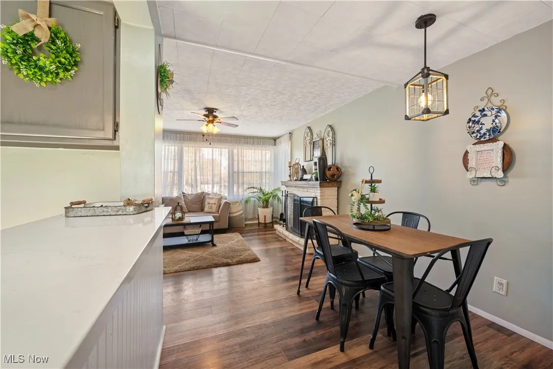 Dining room with dark wood finished floors, a fireplace, and a ceiling fan