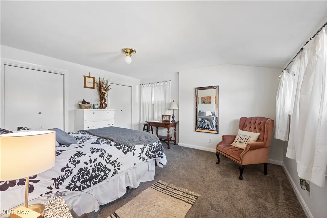 Bedroom featuring a closet, dark carpet, and lofted ceiling