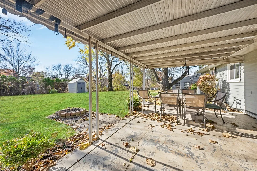 View of patio featuring outdoor dining area, a fire pit, and a storage shed