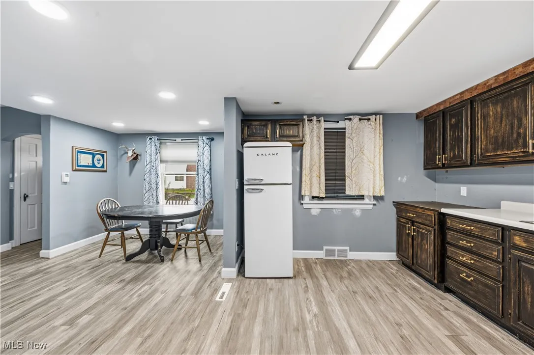 Kitchen featuring dark brown cabinetry, freestanding refrigerator, light wood-type flooring, and recessed lighting