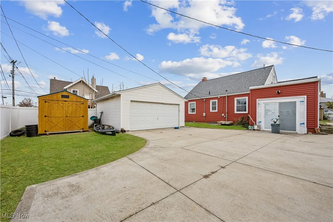 Back of house with a detached garage, a storage shed, a yard, and roof with shingles