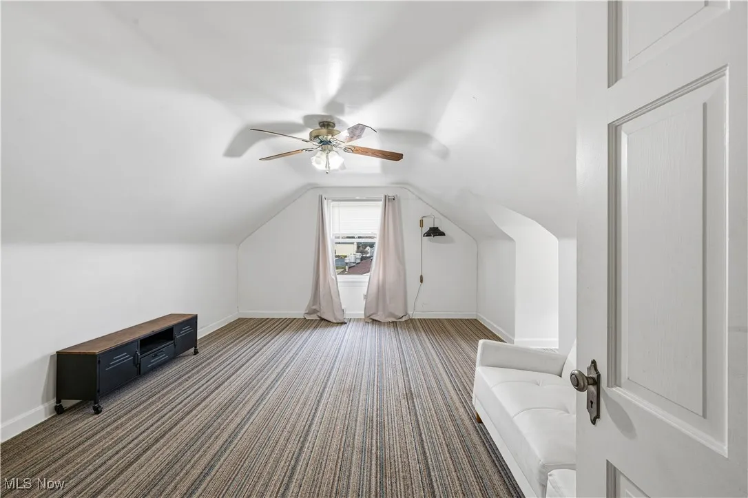 Additional living space featuring vaulted ceiling, carpet, and ceiling fan