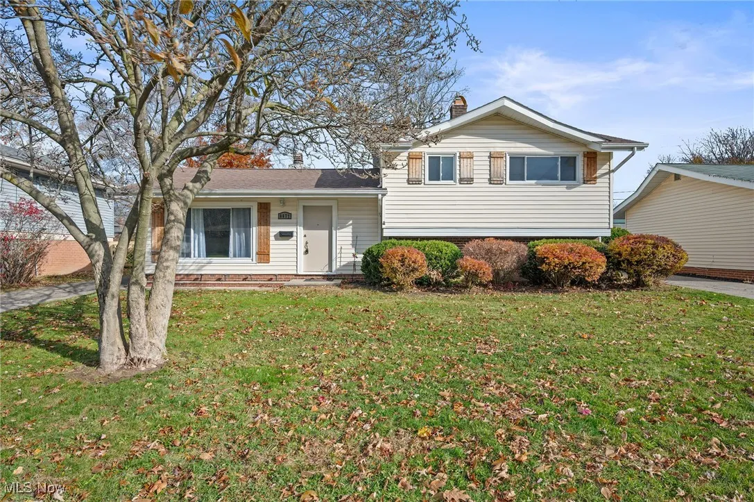 Tri-level home featuring a chimney, a front lawn, and covered porch
