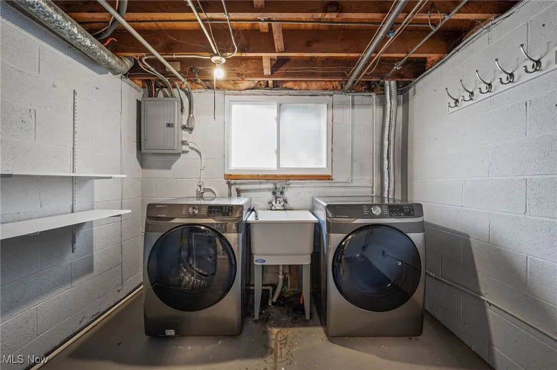 Washroom with concrete floors, electric panel, and independent washer and dryer