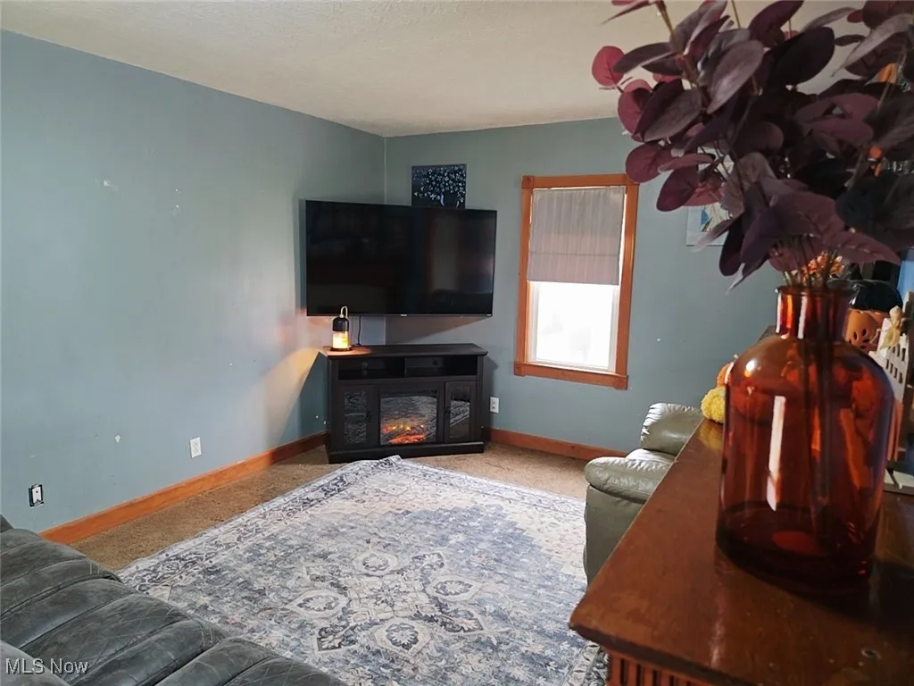 Living area with carpet floors, a lit fireplace, and a textured ceiling