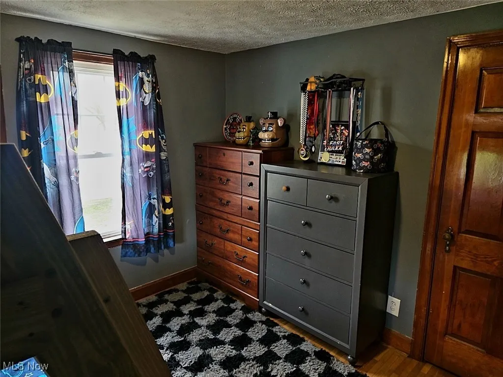 Bedroom with a textured ceiling and wood finished floors