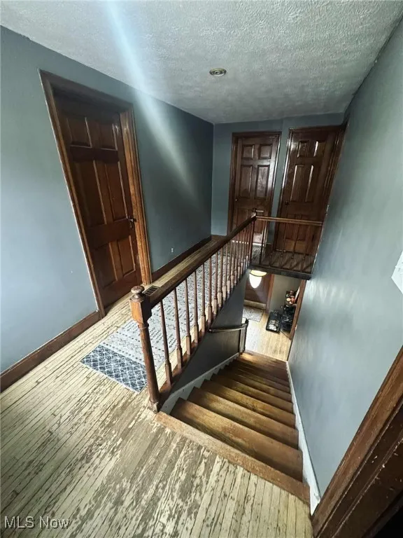 Stairway with wood-type flooring and a textured ceiling
