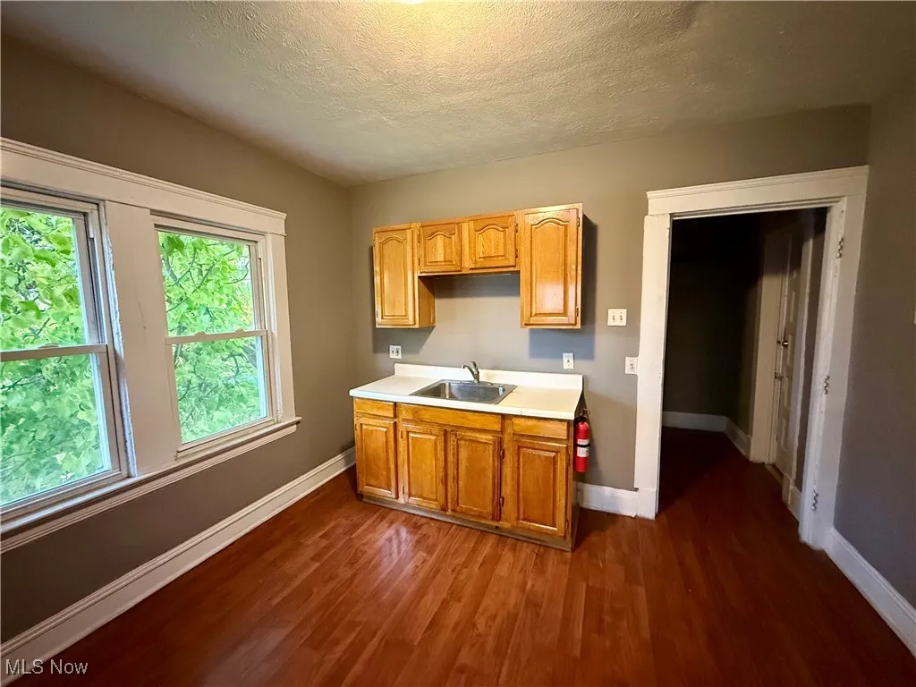 Kitchen with a textured ceiling, light countertops, dark wood-type flooring, and brown cabinets