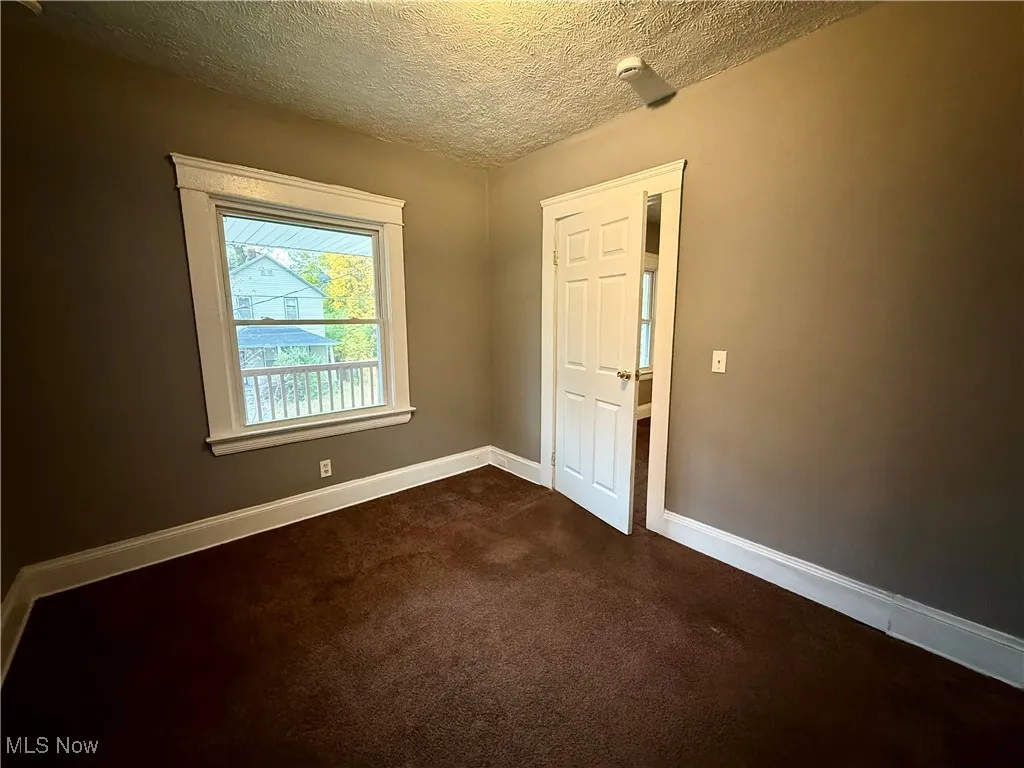 Spare room with a textured ceiling and dark colored carpet