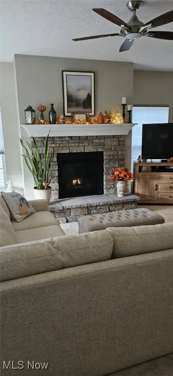 Living room featuring ; a ceiling fan, and a fireplace