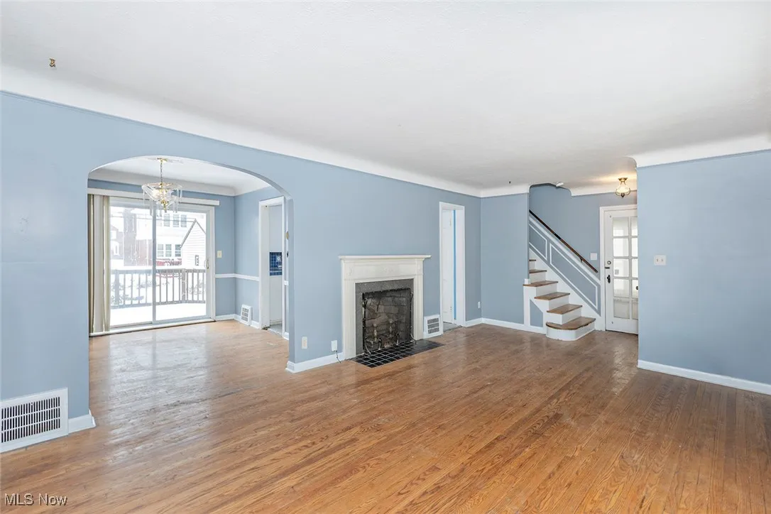 Unfurnished living room featuring a chandelier, wood finished floors, plenty of natural light, and arched walkways